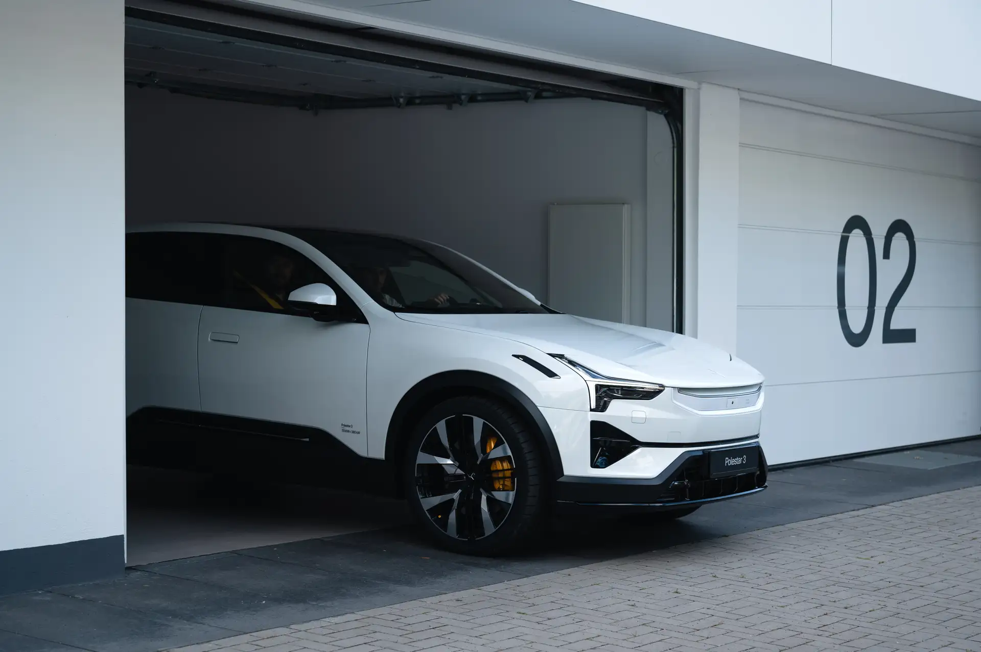 Ein weißer Polestar 3 fährt aus einer Garage. 